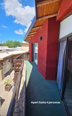 a house with a red wall and a patio at Aparts Aldea Del Montañes in Mina Clavero