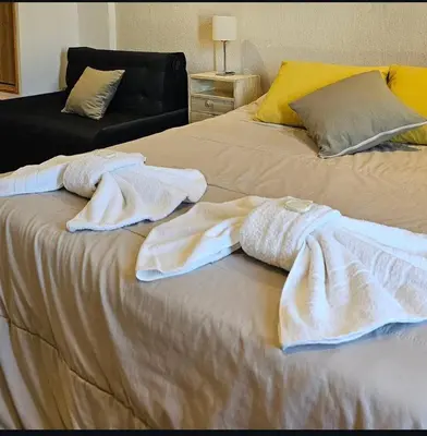 a bed with towels on it with a couch at Aparts Aldea Del Montañes in Mina Clavero