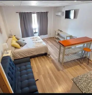 a room with a bed and a desk and a table at Aparts Aldea Del Montañes in Mina Clavero