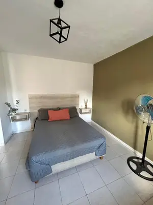 a bedroom with a bed with a red pillow and a lamp at Departamentos M&M in Villa Cura Brochero