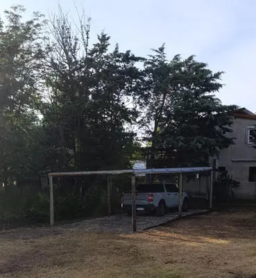 a white suv under a shed in a yard at La casona de Yatel in Santa Rosa de Calamuchita