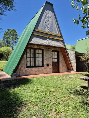 a house with a triangular roof with a grass yard at Alpina 3 segunda usina in Dique Nivelador