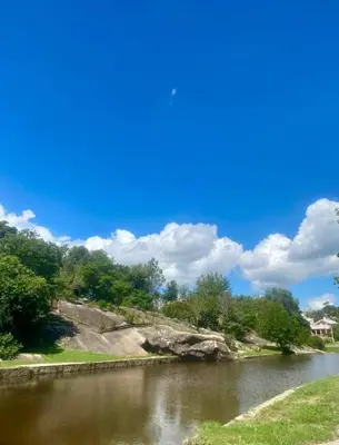 a river with trees and a blue sky with clouds at Happy House in Tanti