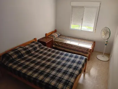 two beds in a room with a fan and a window at Happy House in Tanti