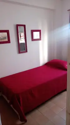 a red bed in a room with two pictures on the wall at Departamento centro Carlos Paz in Villa Carlos Paz