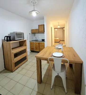 a kitchen with a wooden table and white chairs at Monoambiente Centro in Cordoba