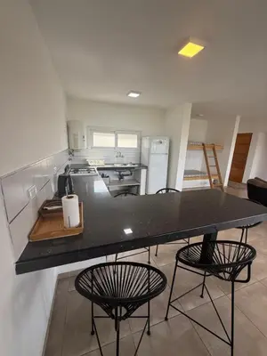 a kitchen with a large black counter and chairs at Chalet de montaña in Villa Carlos Paz