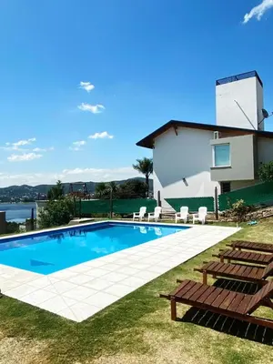 a swimming pool with two chairs and a house at Chalet de montaña in Villa Carlos Paz