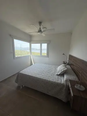 a white bedroom with a bed and a window at Chalet de montaña in Villa Carlos Paz