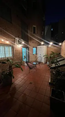 a patio at night with two chairs and lights at Duarte Quiros Apartamento in Cordoba