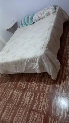 a bed with a white comforter on a wooden floor at Abu Ma! in Tanti