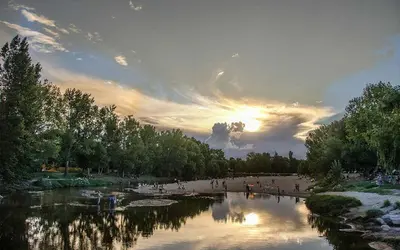 a group of people walking on a river at sunset at Mina Clavero Chalet in Mina Clavero
