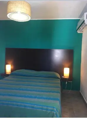 a bedroom with a bed with a green wall and two lamps at Complejo Don otto in Cavalango