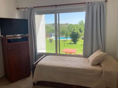 a bedroom with a large window with a bed and a television at Complejo Don otto in Cavalango