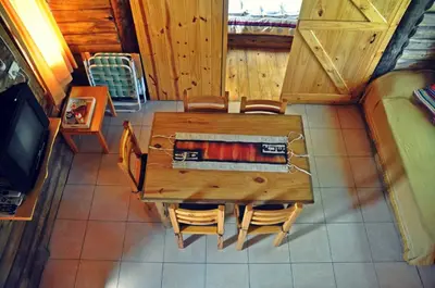 a wooden table and chairs in a room with a tv at Enkel Cabañas in José de la Quintana