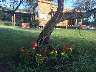 a log cabin with flowers in front of it at Enkel Cabañas in José de la Quintana