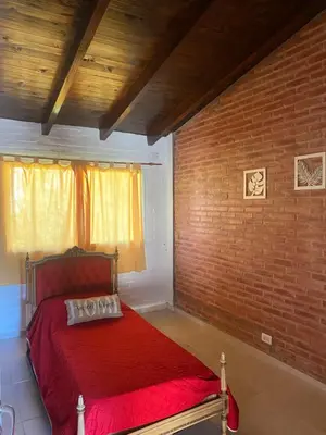 a red bed in a room with a brick wall at Departamento frente al rio solo familias in Villa Carlos Paz