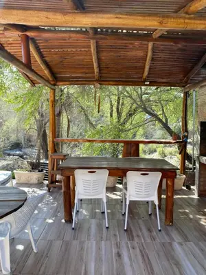 a wooden table and chairs on a wooden deck at Departamento frente al rio solo familias in Villa Carlos Paz