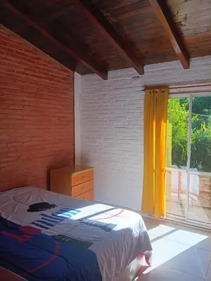 a bedroom with a bed and a window with yellow curtains at Departamento frente al rio solo familias in Villa Carlos Paz