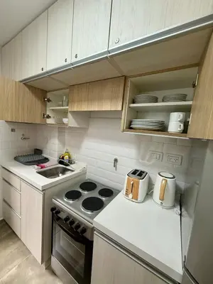 a kitchen with white cabinets and a stove top oven at Departamento en el corazón de Nueva Cordoba SS8 in Cordoba