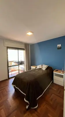 a bedroom with a large bed with a blue wall at Departamento en Guemes in Cordoba