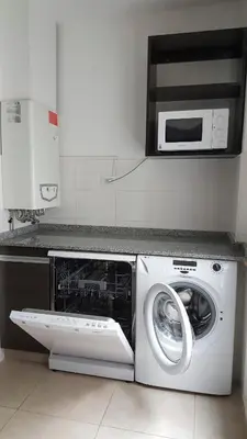 a kitchen with a washing machine and a microwave at Amplio departamento frente al lago-seguridad 24hs in Villa Carlos Paz