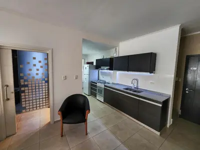 a kitchen with a sink and a chair in a room at Amplio departamento frente al lago-seguridad 24hs in Villa Carlos Paz