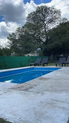 a swimming pool with two benches and a tree at Casa calma in Villa de Las Rosas