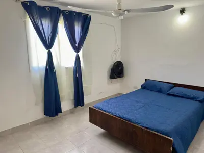 a bedroom with a bed with blue sheets and a window at La Casa De Juan in Mina Clavero