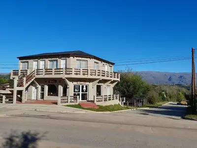a large white building with a balcony on a street at Posada Villa Yacanto in Villa Yacanto