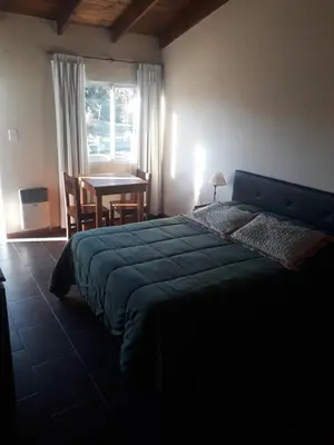 a bedroom with a bed and a table and a window at Posada Villa Yacanto in Villa Yacanto