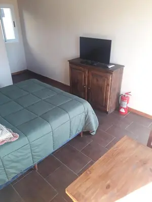 a bedroom with a bed and a tv and a table at Posada Villa Yacanto in Villa Yacanto