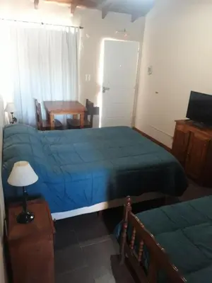 a bedroom with two beds and a table and a desk at Posada Villa Yacanto in Villa Yacanto