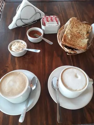 a table with two cups of coffee and toast at Posada Villa Yacanto in Villa Yacanto