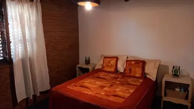 a bedroom with a bed with a red comforter at La Cabaña de EMI in La Bolsa