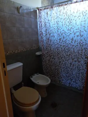 a bathroom with a toilet and a shower curtain at La Cabaña de EMI in La Bolsa