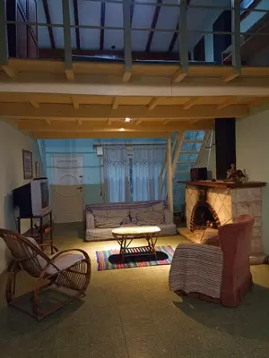 a living room with a fireplace and a table and chairs at Portal de las sierras in Bialet Massé