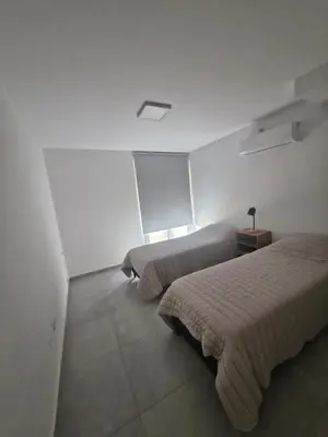 two beds in a room with white walls at DEPARTAMENTO Villa Carlos Paz altos de Lincoln in Villa Carlos Paz