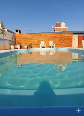a swimming pool with two white chairs in the background at Cabañas los materos 2 in Cordoba