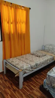 a bed in a room with an orange curtain at Cabañas los materos 2 in Cordoba