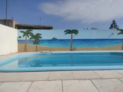 a swimming pool with a mural of a beach and palm trees at Cabañas los materos 2 in Cordoba