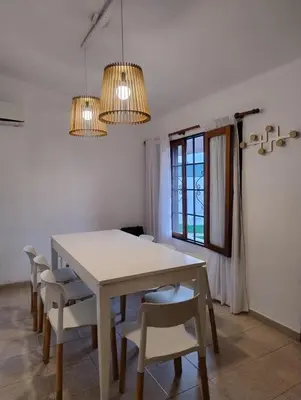 a dining room with a white table and chairs at Casa con pileta cómoda y equipada in Villa Carlos Paz