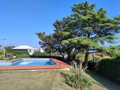 a swimming pool in a yard with a tree at Casa con pileta cómoda y equipada in Villa Carlos Paz