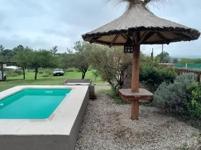 an umbrella and a bench next to a swimming pool at Alquiler temporario tanti in Villa Carlos Paz