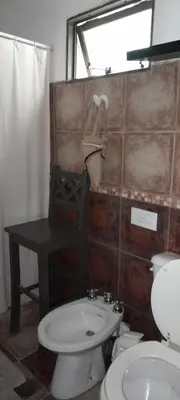 a bathroom with a toilet and a sink and a window at Alquiler temporario tanti in Villa Carlos Paz