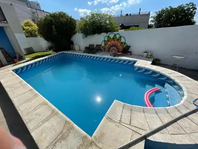 a large blue swimming pool with a red poolvisor at El Jorgito in Villa Carlos Paz