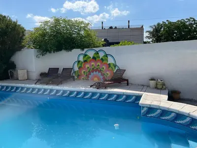 a pool with two chairs and a painting on a wall at El Jorgito in Villa Carlos Paz