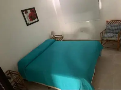 a bedroom with a blue bed and a chair at El Jorgito in Villa Carlos Paz
