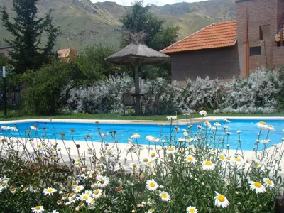a blue swimming pool with a gazebo and flowers at Rumbo 020 Apart in Merlo