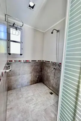 a bathroom with a shower and a tiled floor at Rumbo 020 Apart in Merlo